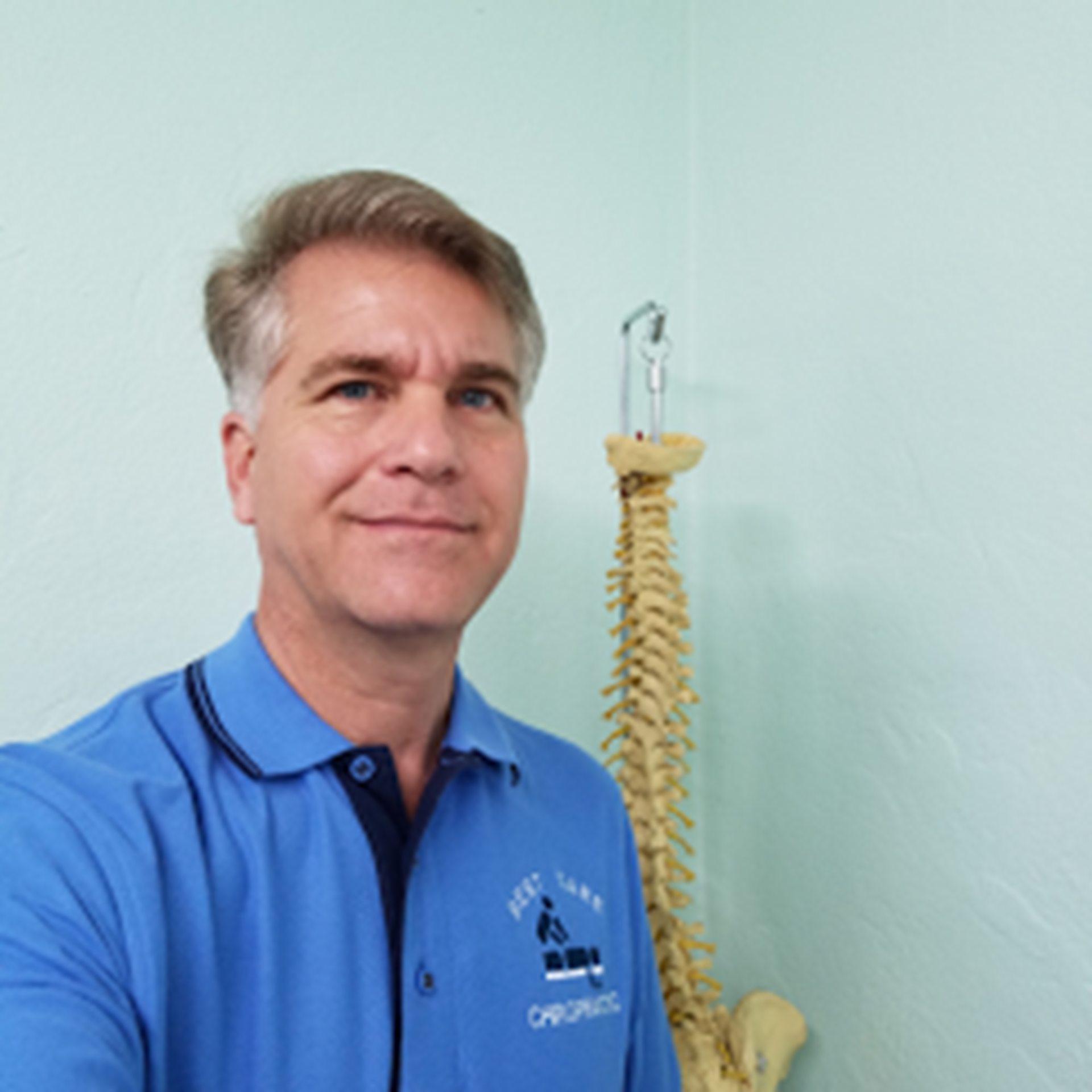 Dr. Todd Tomburo, chiropractor, holding a spine model